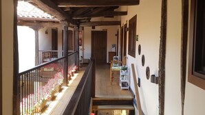 Un couloir avec des poutres en bois, un balcon orné de fleurs et un escalier.