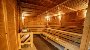 A wooden sauna with benches and a bench with a bucket. - Lind Hotel (Rietberg)
