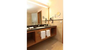Un baño de hotel con un espejo grande, dos lavamanos y un perchero para toallas.