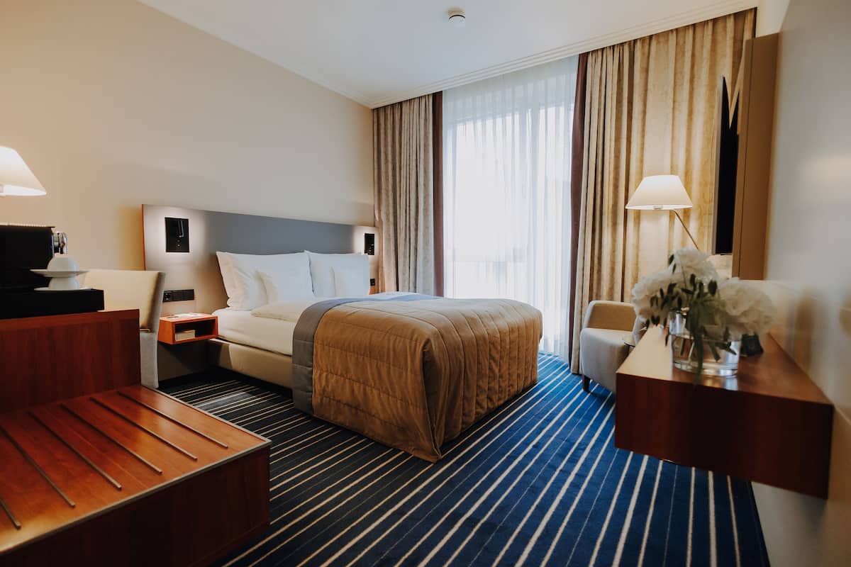 A hotel room with a bed, bedside tables, a desk, and a chair.