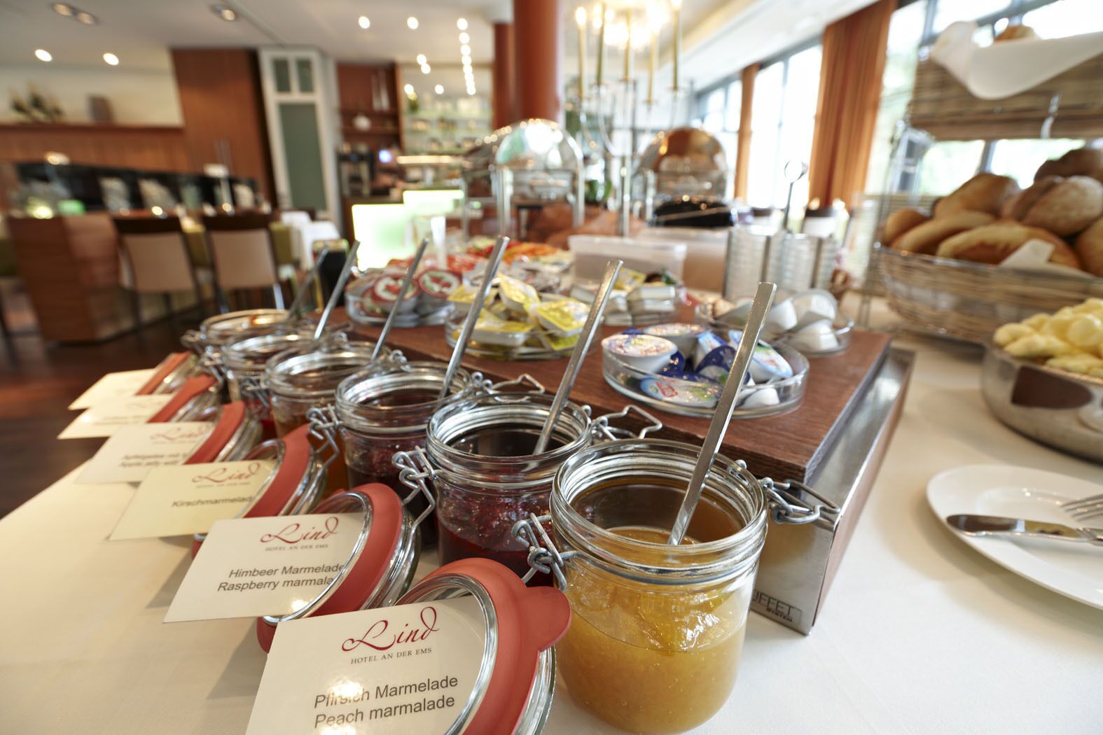 A buffet with various food items and labeled jars of jams.