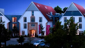 A row of modern houses with distinct architectural styles, including a prominent building with a red roof and a visible entrance. - Lind Hotel (Rietberg)