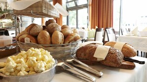 A buffet table with various breads, pastries, and a bowl of cream puffs. - Lind Hotel (Rietberg)