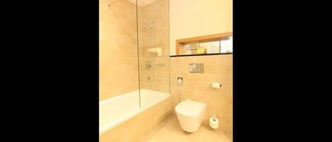 A bathroom with a glass shower enclosure, a toilet, and a sink area.
