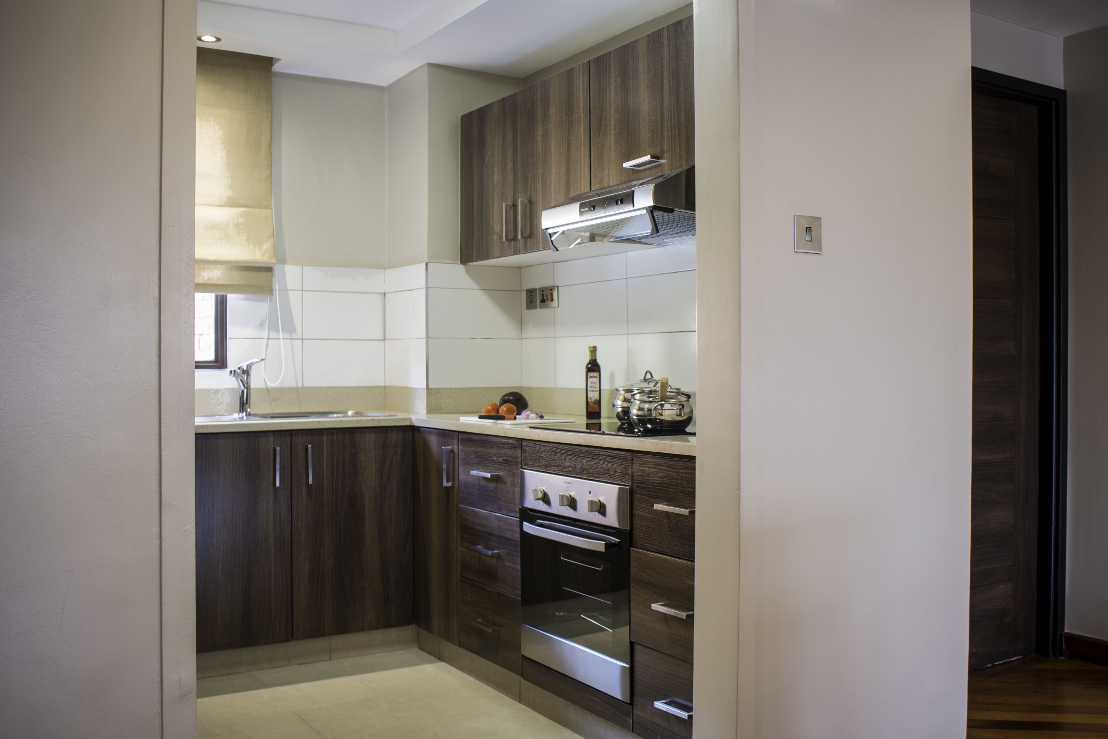 A modern kitchen with dark wooden cabinets, stainless steel appliances, and a tiled backsplash.