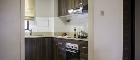 A modern kitchen with dark wooden cabinets, stainless steel appliances, and a tiled backsplash.
