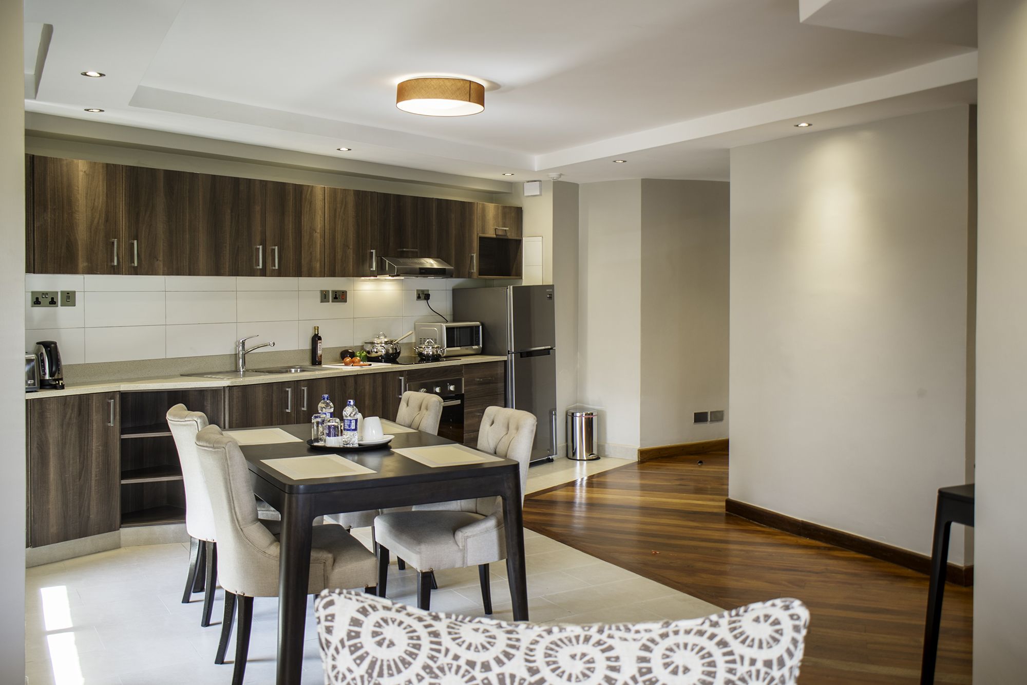 A modern kitchen with dark wood cabinets, a central island, and a dining area with a table and chairs.