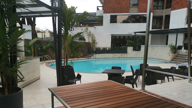 Et poolområde med træterrasse, liggestole og pool.