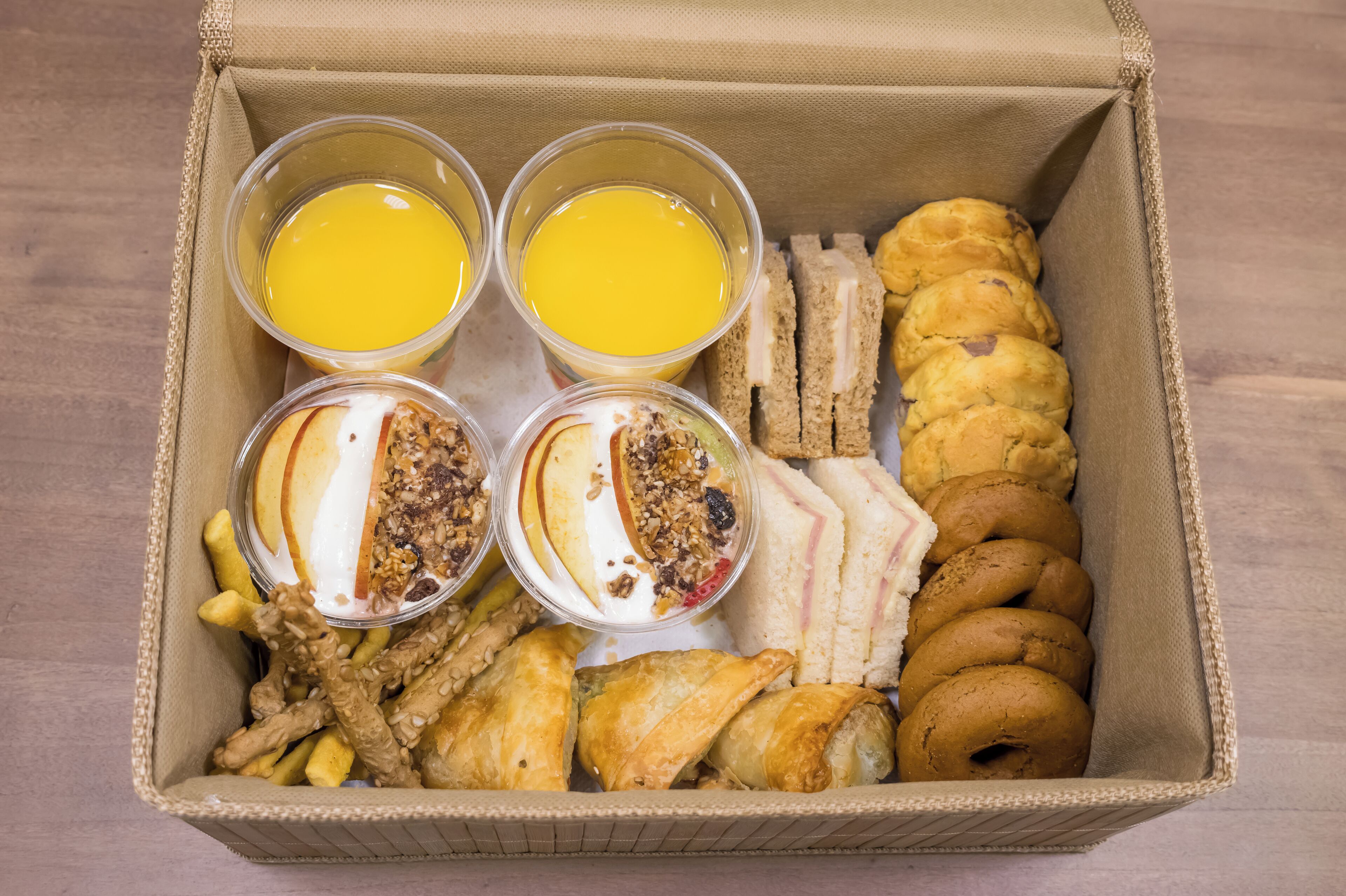 A box containing breakfast items including croissants, bagels, and fruit.