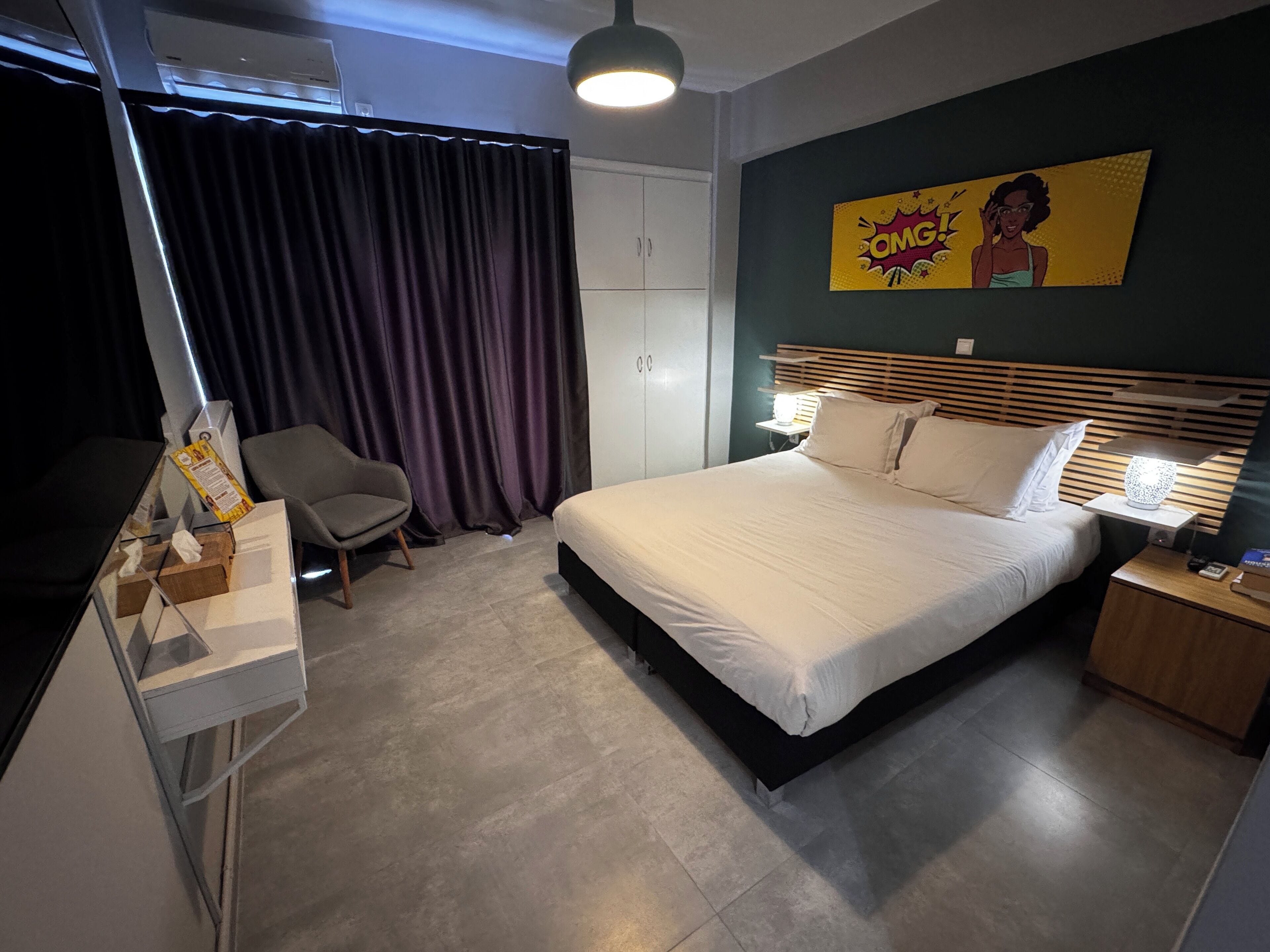 Una habitación de hotel moderna con una cama, una silla, un escritorio y un armario.