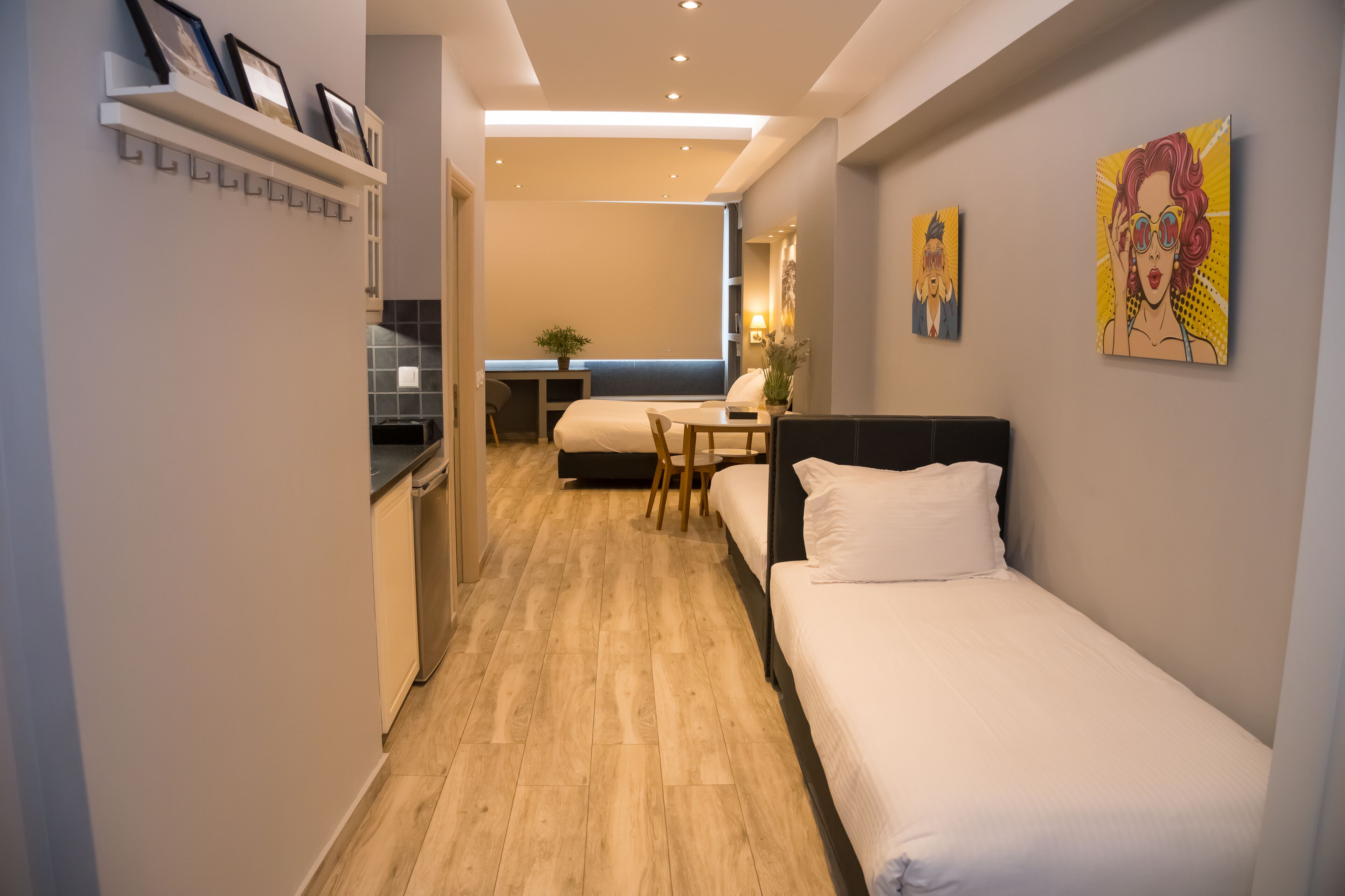 Een moderne hotelkamer met een houten vloer, een bed, een bureau en een klein zithoekje.