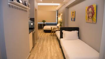 Een moderne hotelkamer met een houten vloer, een bed, een bureau en een klein zithoekje.