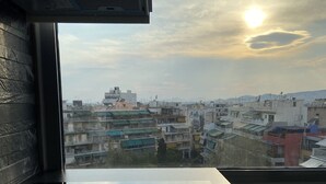 A view from a window overlooking a cityscape with buildings and a clear sky. - Connect Studios & Apartments (Athens)