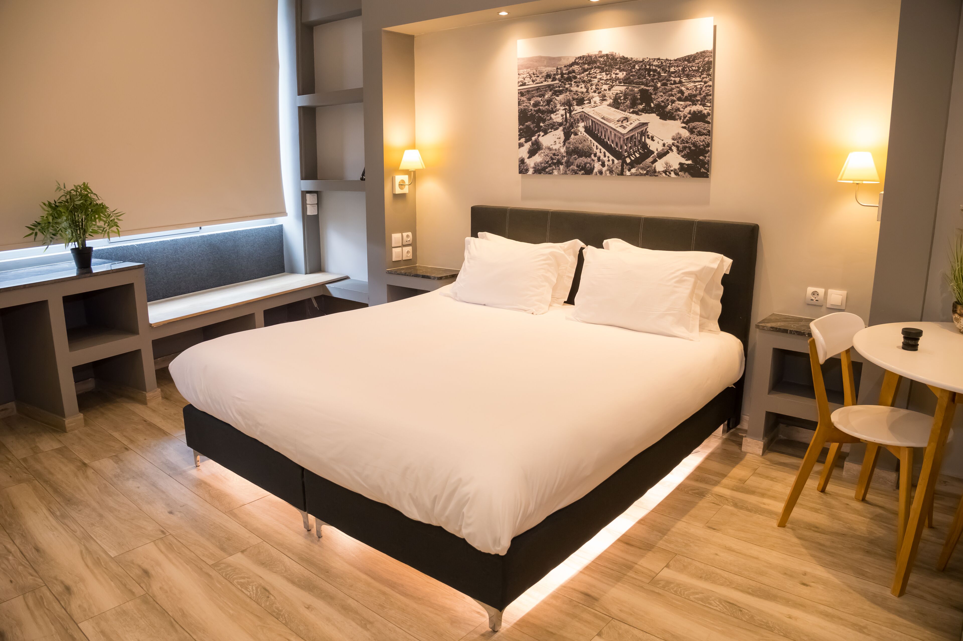 Una habitación de hotel moderna con una cama grande, mesitas de noche, un escritorio pequeño y una silla.