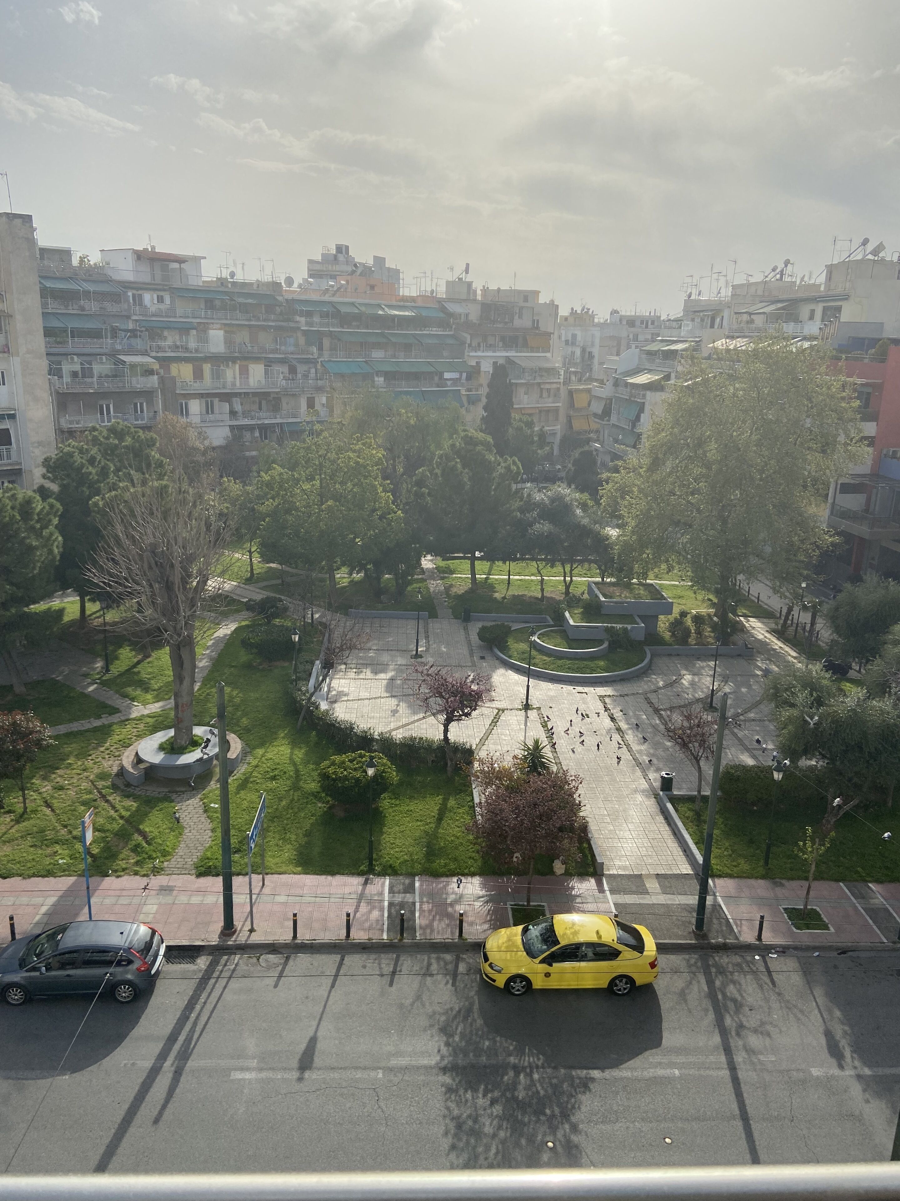 A residential area with multi-story buildings, a central roundabout, and a parking lot with cars.