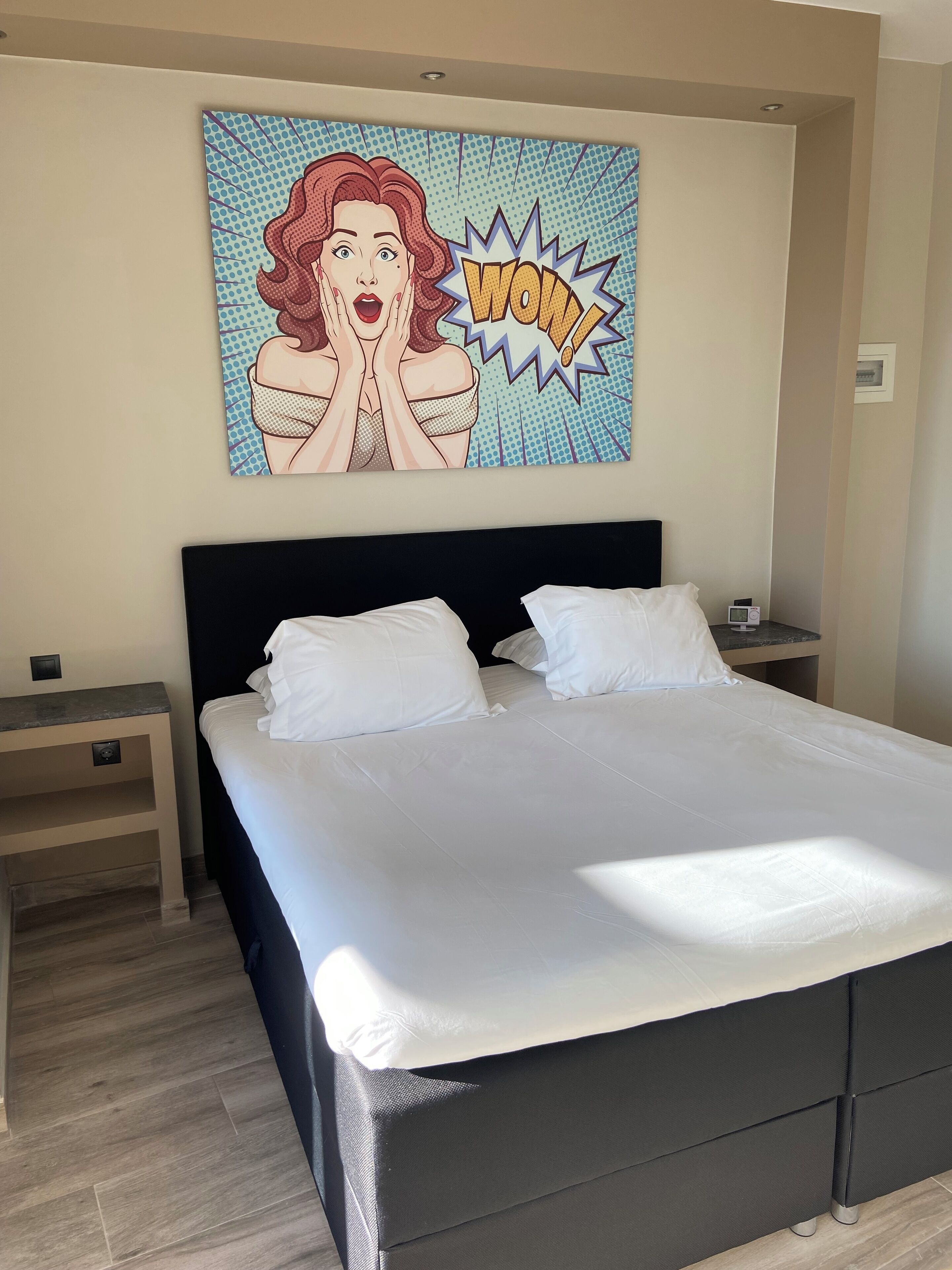 Une chambre à coucher avec un lit, des oreillers blancs, une table de chevet et une œuvre d’art murale.