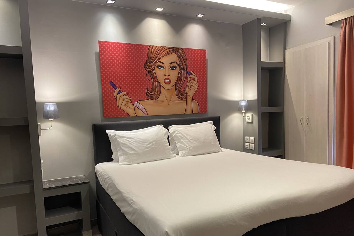 Un dormitorio moderno con una cama grande, una mesita de noche, un armario y un cuadro colgado en la pared.