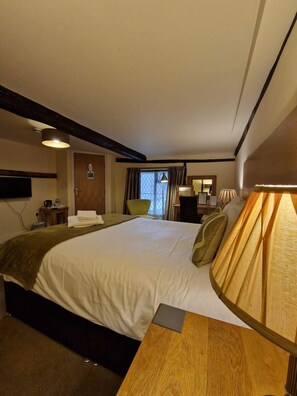 A hotel room with a large bed, a wooden nightstand, a desk, a chair, a TV, and a window with curtains. - The North Hill Hotel, Colchester (Colchester)