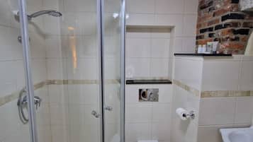 A bathroom with a glass-enclosed shower, a toilet, and a sink.