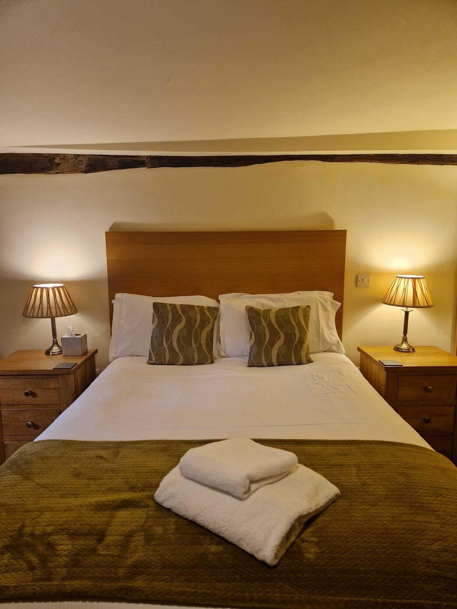 A hotel room with a large bed, two bedside tables, and two lamps.