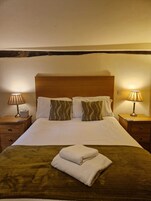 Una habitación de hotel con una cama grande, dos mesitas de noche y dos lámparas.
