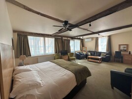 Una habitación de hotel con una cama grande, un escritorio, una silla, un sofá y un ventilador de techo.