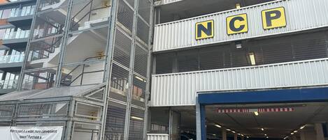 A multi-level parking garage with a sign indicating 'NCP' and a banner advertising 'Premier Parking Space.'