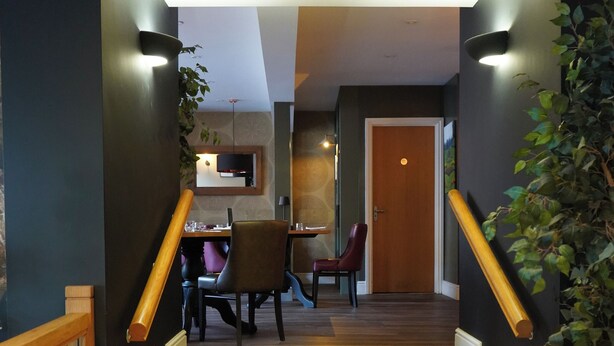 A staircase with wooden steps and a handrail, leading to a dining area with a table and chairs. - The North Hill Hotel, Colchester (Colchester)