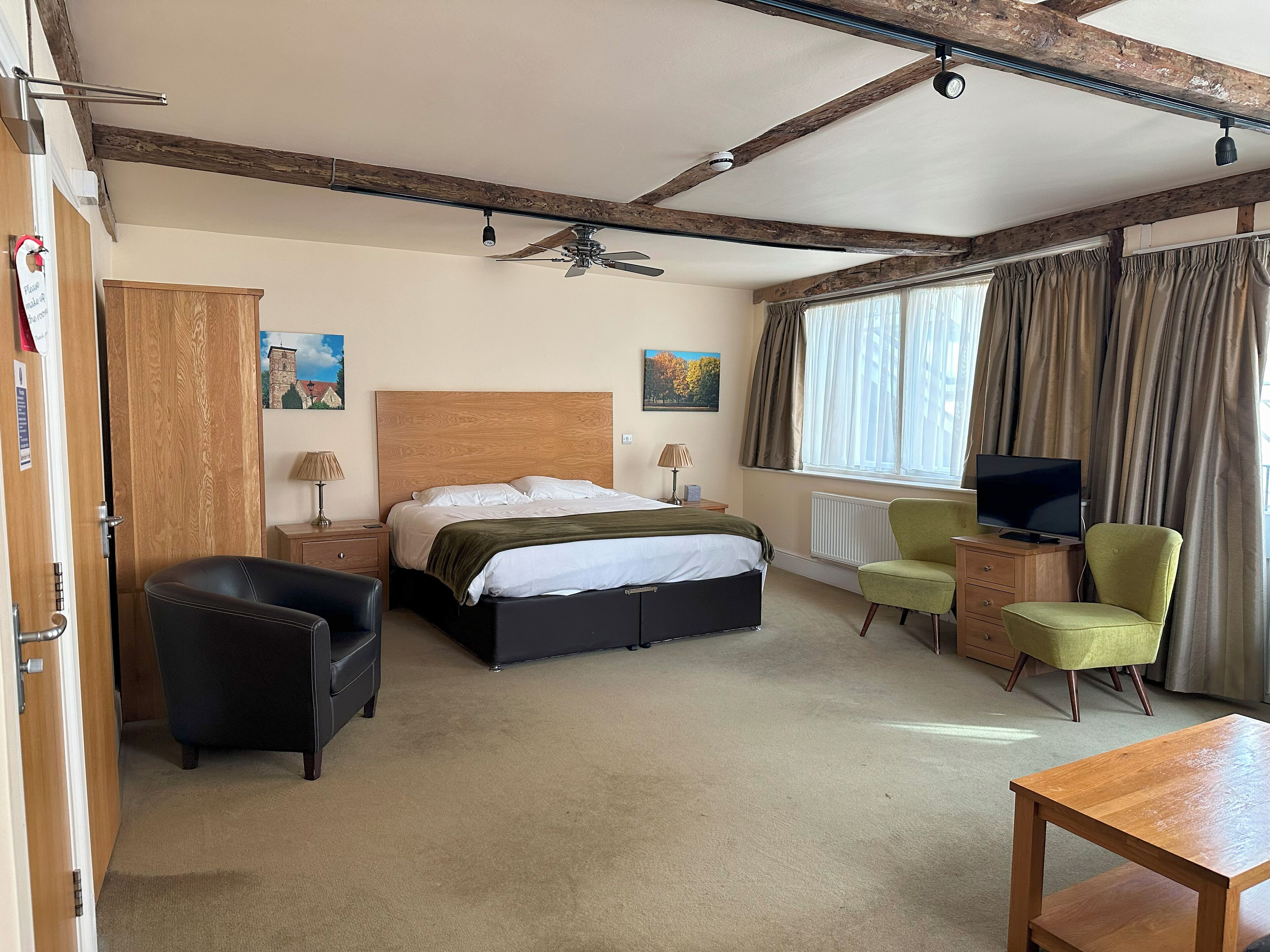 Une chambre d’hôtel équipée d’un lit, d’un bureau, d’une chaise, d’une télévision et d’une fenêtre avec des rideaux.