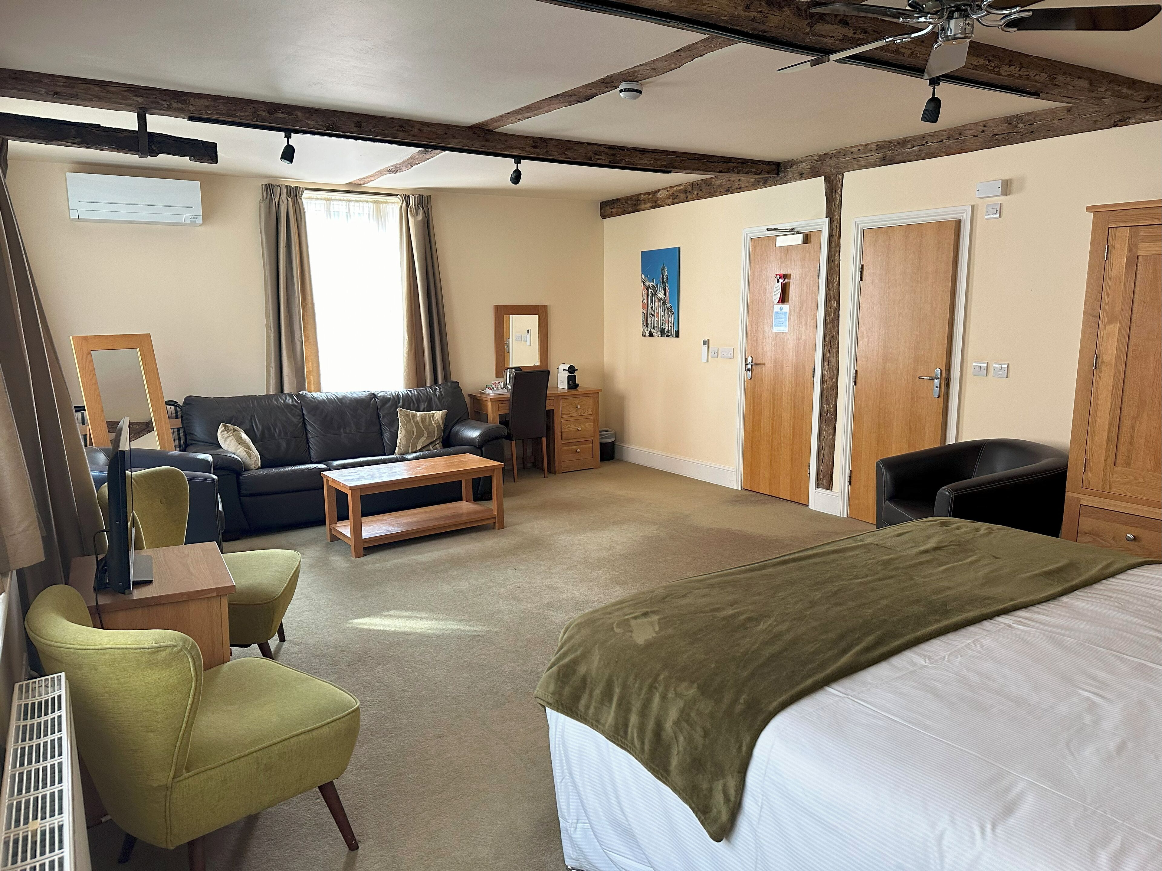 Una habitación de hotel con cama, sofá, escritorio, silla y ventilador de techo.