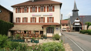 A hotel with a traditional facade, a visible entrance, and a church steeple in the background. - Auberge Saint Martin (Saint-Martin-Terressus)