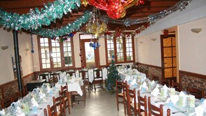 A dining area with multiple tables set for a meal, decorated with festive garlands and a Christmas tree. - Auberge Saint Martin (Saint-Martin-Terressus)