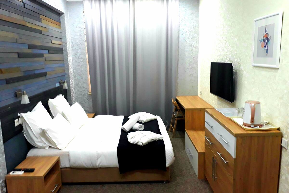 A hotel room with a bed, a desk, a television, and a coffee maker.