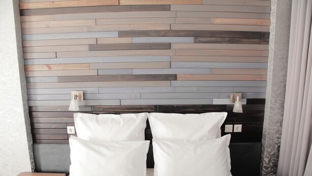 A neatly made bed with white linens and two bedside lamps. - Small Hotel Bishkek (Bishkek)