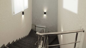 A stairwell with a handrail, a wall-mounted light, and a radiator. - Small Hotel Bishkek (Bishkek)