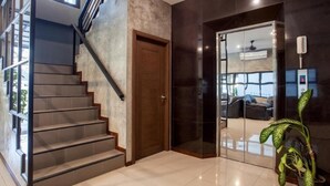 Un interior moderno con una escalera, un vidrio que da a una sala de estar y una planta en maceta.