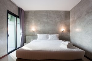 Une chambre moderne avec un grand lit, deux lampes fixées au mur et une vue à travers une porte vitrée.
