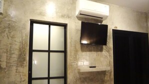 Una habitación con un ventanal amplio, un equipo de aire acondicionado y un televisor montado.