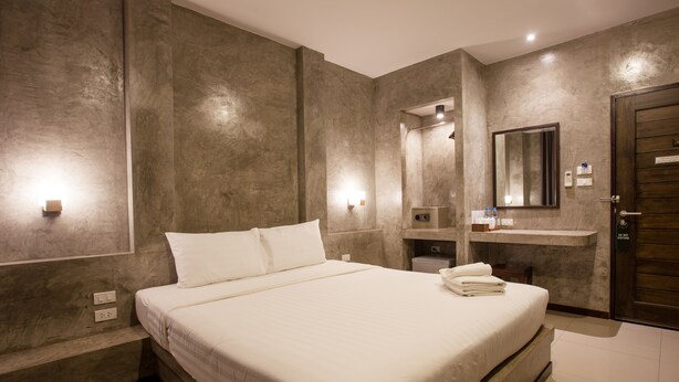 Una habitación de hotel moderna con una cama grande, un tocador empotrado con espejo y una puerta de madera.