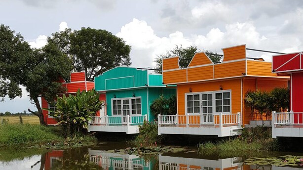 Une rangée de maisons colorées bordant un plan d’eau paisible, dont les reflets se mirent à la surface.