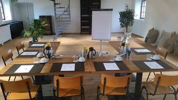A conference room with a long table set for a meeting, equipped with coffee makers, cups, and papers.