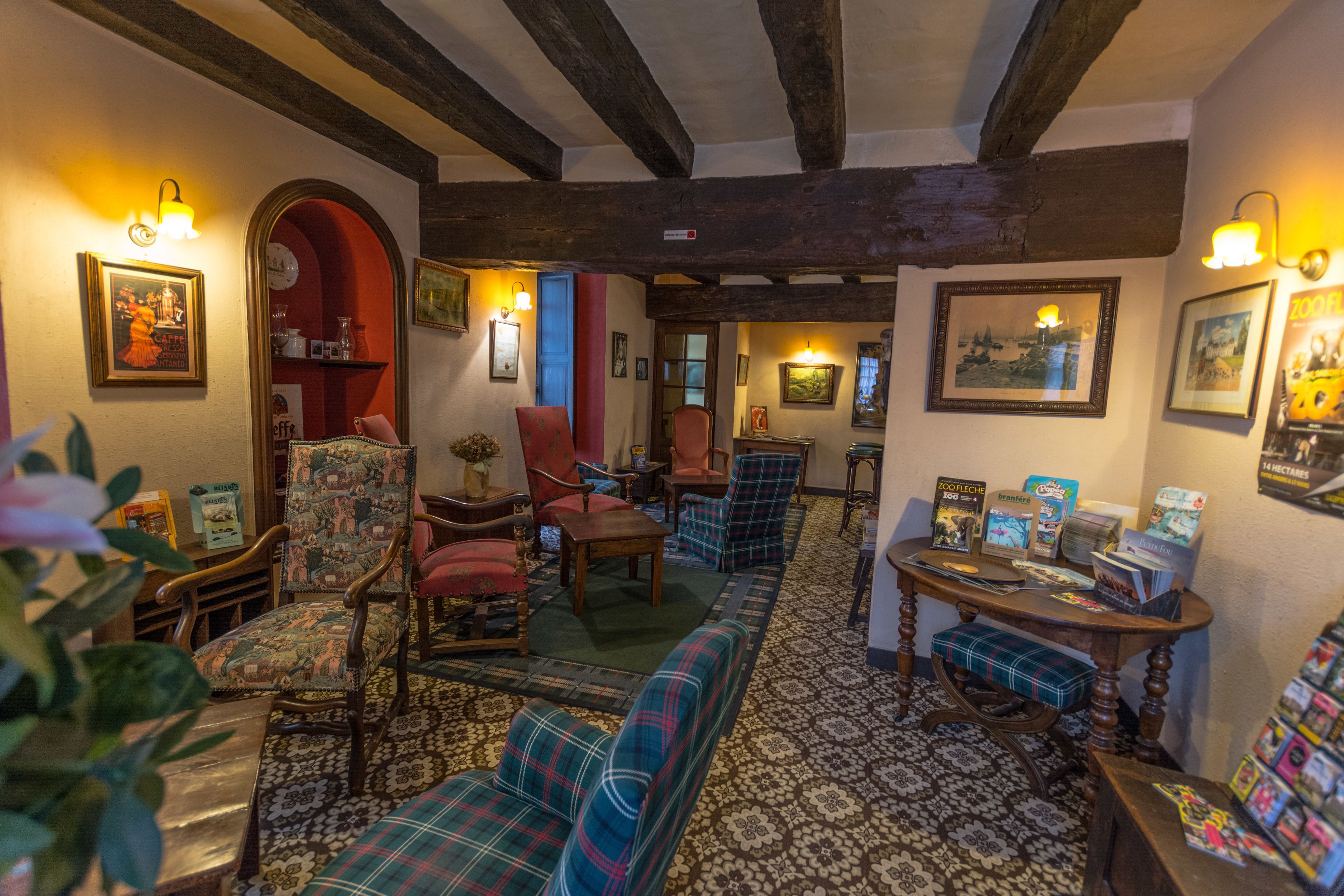 A traditional inn with wooden beams, a patterned floor, and various seating arrangements including a sofa and chairs.