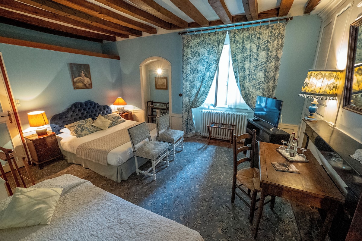 A bedroom with a bed, bedside tables, a chair, a table, and a window with curtains.