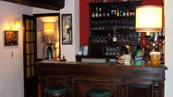Una zona de bar con taburetes de madera, una estantería de licores y una lámpara.