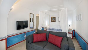 Un dormitorio con una cama, televisor, sofá y mesita de noche.