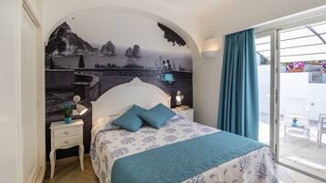 Un dormitorio con cama, mesitas de noche, un mural y vistas a través de un ventanal.