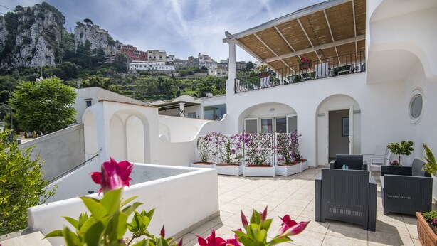 Una terraza en la azotea con mobiliario exterior, piscina y vistas del paisaje circundante.