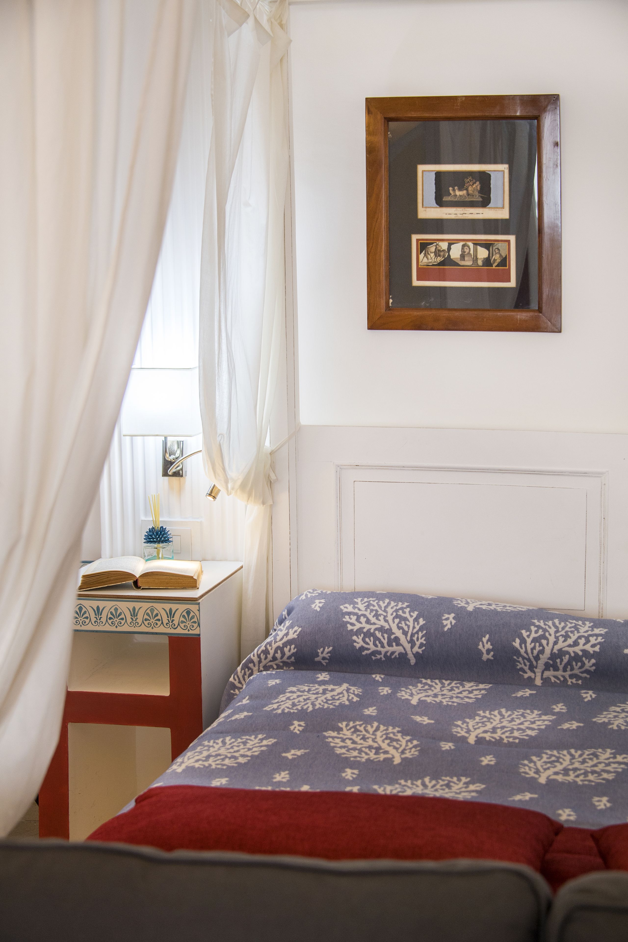 A bedroom with a bed, a bedside table with a book, and a framed picture on the wall.