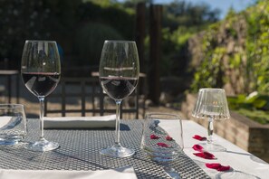Tres copas de vino sobre una mesa con superficie de metal, rodeadas de pétalos de rosa.