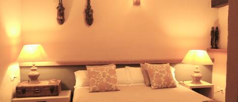 A hotel room with a bed, two bedside tables, a nightstand, a wall-mounted light, and a ceiling fan.